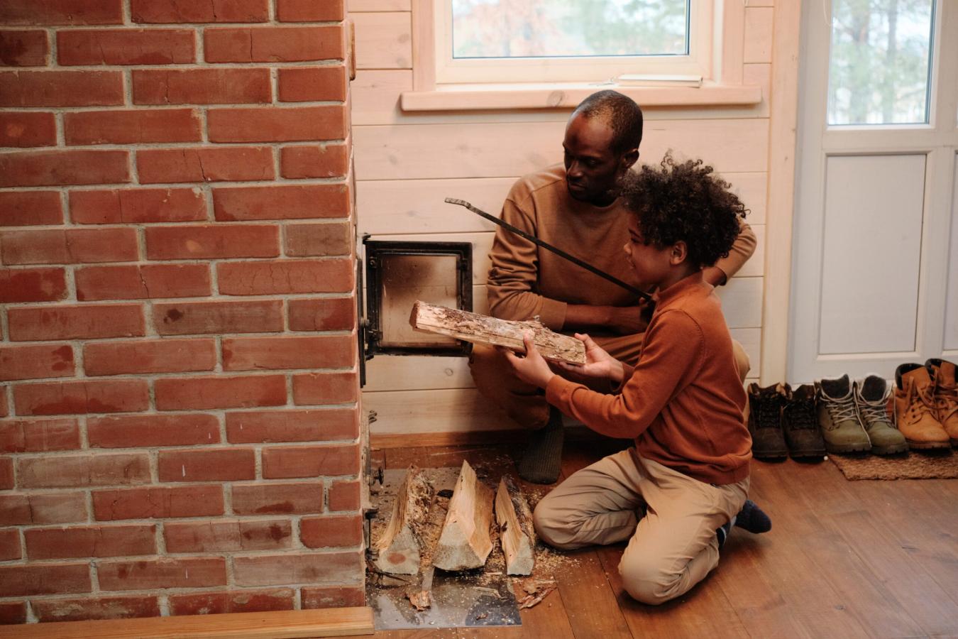 father and son placing wood in log burner