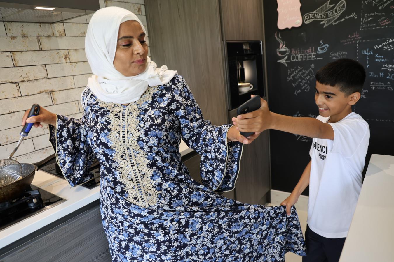Lady cooking in the kitchen distracted by child.